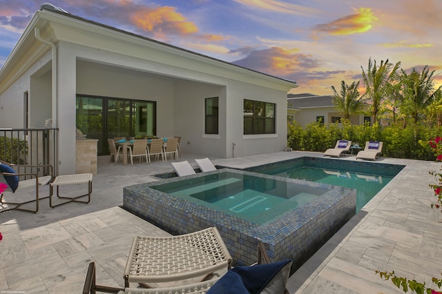 13173 Faberge Pl, Palm Beach Gardens, FL 33418 - pool at dusk with an in-ground hot tub, a patio, outdoor dining area, and an outdoor pool