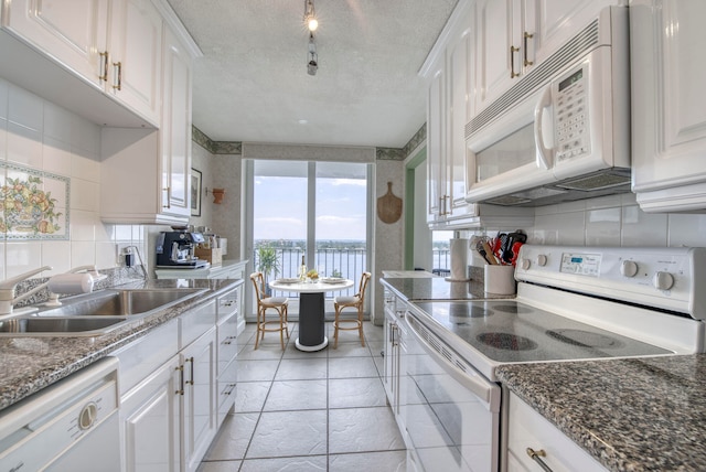 kitchen with white cabinetry, tasteful backsplash, a textured ceiling, light tile patterned floors, and white appliances