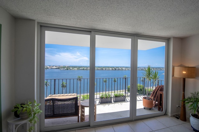 doorway featuring light tile patterned floors, a healthy amount of sunlight, a textured ceiling, and a water view