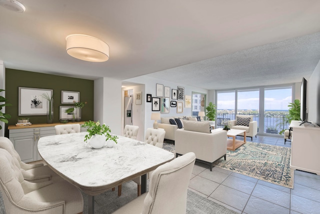 dining area featuring a textured ceiling, floor to ceiling windows, and light tile patterned floors