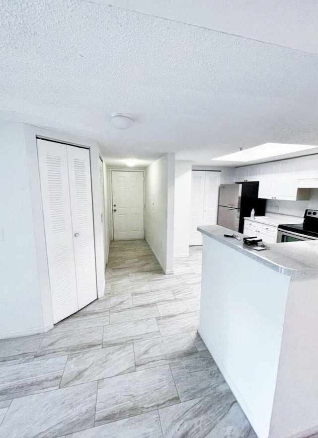 kitchen with white cabinetry, a textured ceiling, custom range hood, stainless steel appliances, and light tile flooring