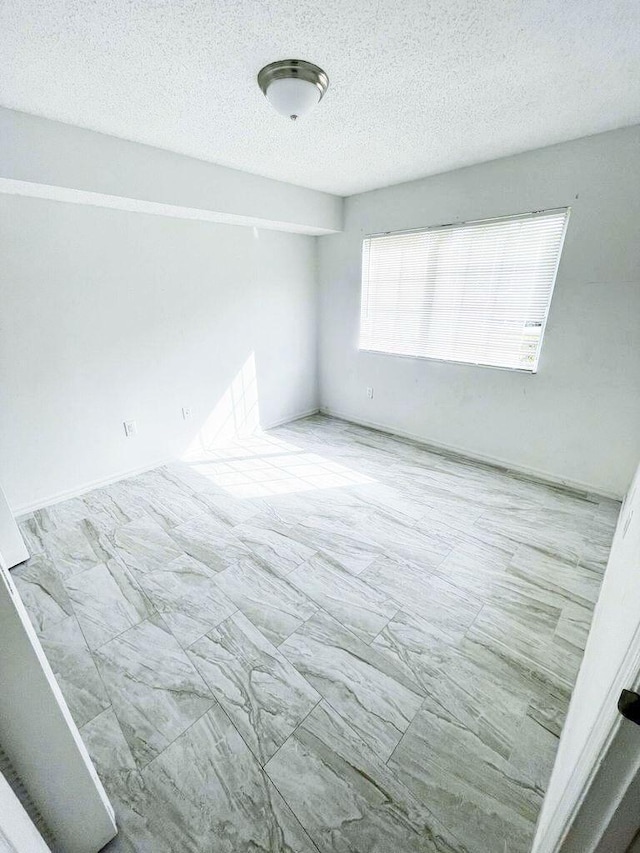 tiled empty room with a textured ceiling