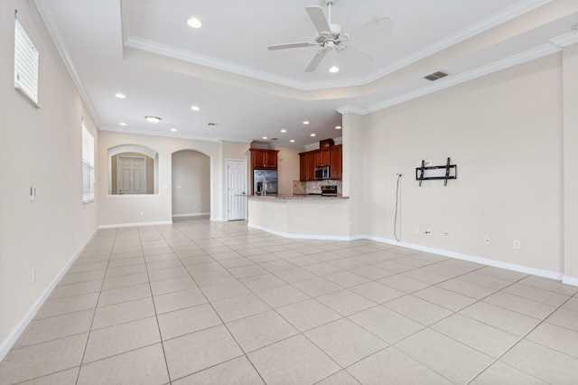 unfurnished living room with a tray ceiling, crown molding, and light tile patterned flooring