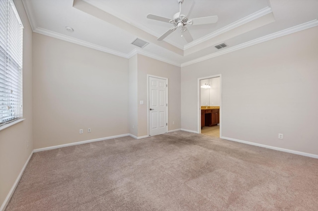 unfurnished bedroom featuring ceiling fan, ornamental molding, ensuite bathroom, and a tray ceiling