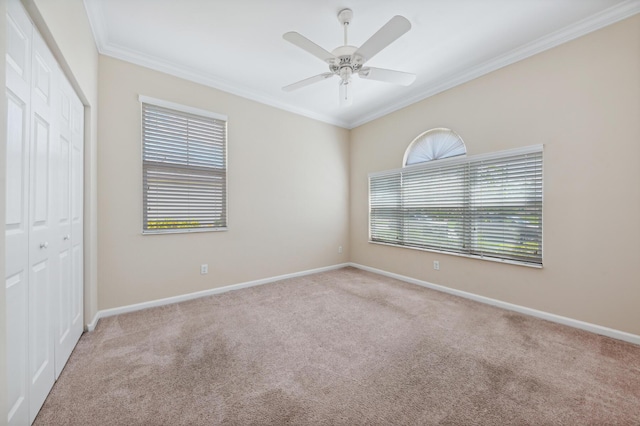 unfurnished bedroom featuring multiple windows, a closet, ceiling fan, and ornamental molding