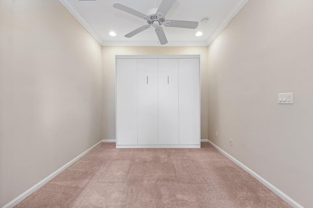 unfurnished bedroom featuring ceiling fan, crown molding, light carpet, and a closet