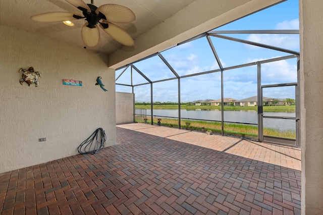 view of patio with ceiling fan, a water view, and glass enclosure