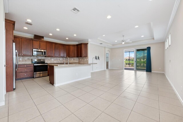 kitchen featuring ceiling fan, stainless steel appliances, light stone counters, crown molding, and a tray ceiling