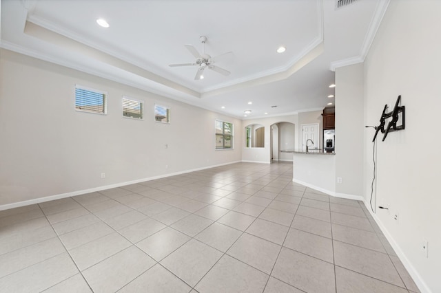 unfurnished living room with a raised ceiling, ceiling fan, crown molding, sink, and light tile patterned floors