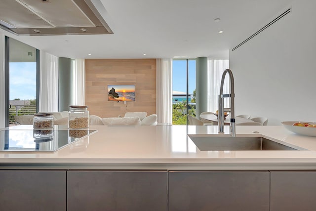 kitchen with a healthy amount of sunlight, sink, and wall chimney range hood