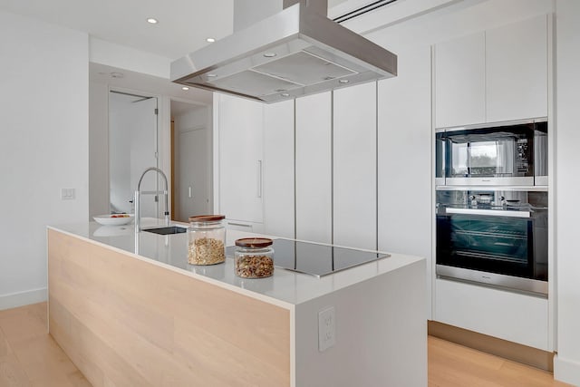 kitchen featuring a kitchen island with sink, light hardwood / wood-style flooring, stainless steel appliances, island range hood, and white cabinets