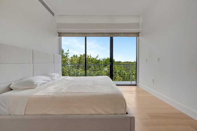 bedroom with light wood-type flooring, multiple windows, and access to outside