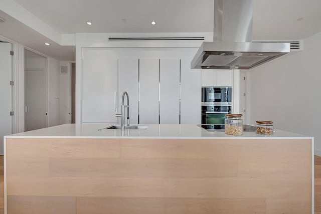 kitchen featuring a center island with sink, black appliances, sink, and island exhaust hood