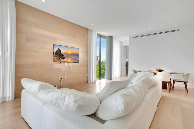 living room featuring wooden walls, a wall of windows, and light hardwood / wood-style floors