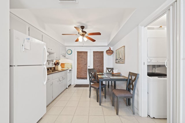 kitchen with french doors, white appliances, white cabinetry, and stacked washer / dryer