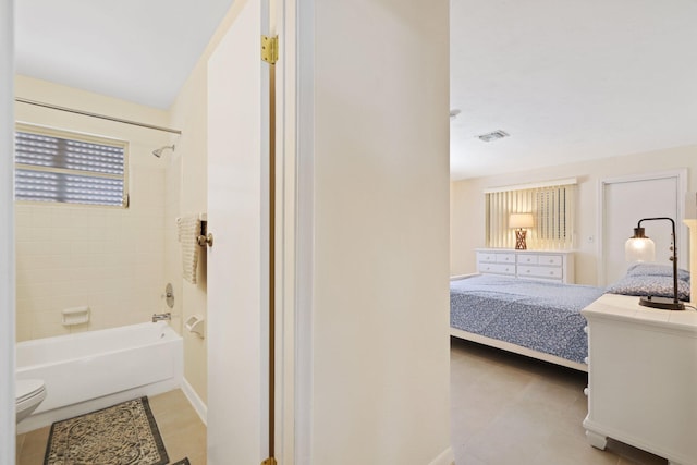 bathroom with tiled shower / bath combo and toilet