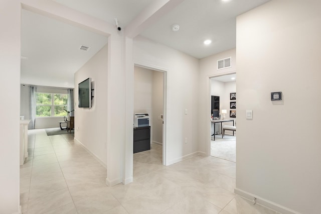 hall featuring beam ceiling and light tile patterned floors