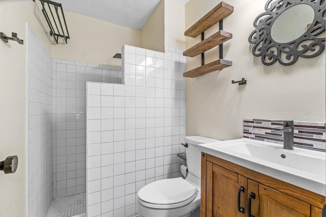 bathroom with vanity, toilet, a tile shower, and tile walls