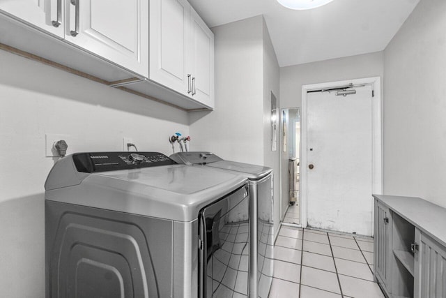 laundry area with washer and dryer, light tile patterned floors, and cabinets