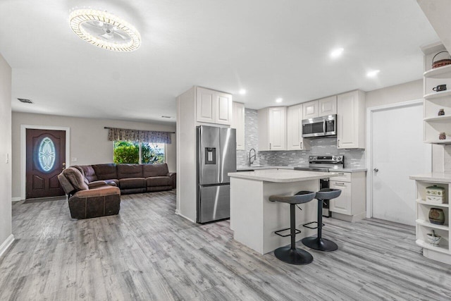 kitchen with a kitchen bar, appliances with stainless steel finishes, a center island, and white cabinetry