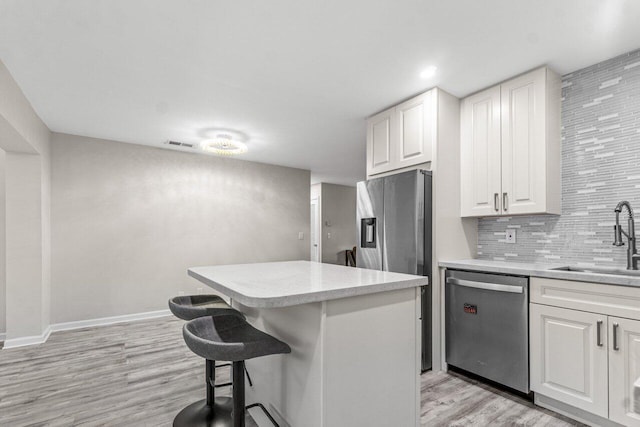 kitchen featuring a breakfast bar, white cabinets, sink, appliances with stainless steel finishes, and light hardwood / wood-style floors