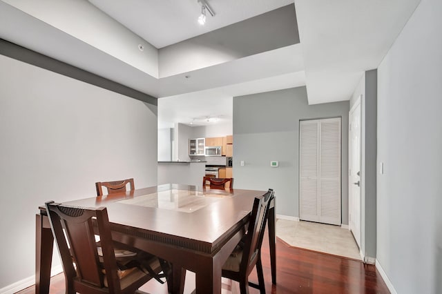 dining area featuring baseboards, track lighting, and wood finished floors