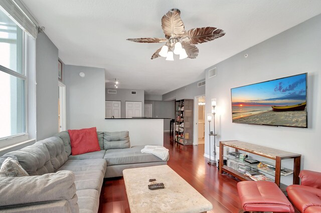 living room with ceiling fan and dark wood-type flooring