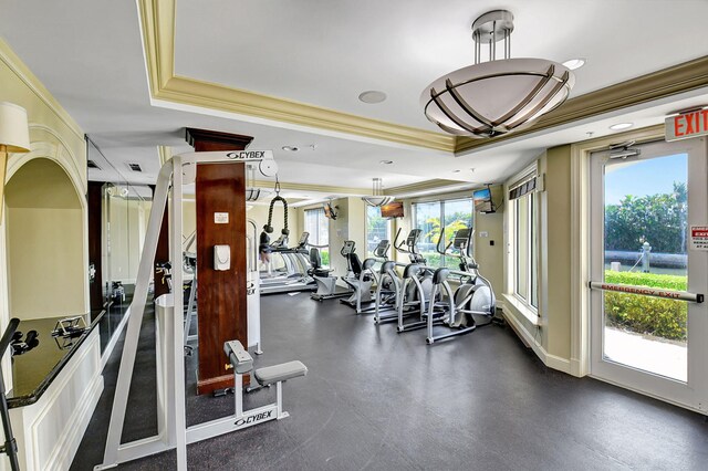 gym featuring a tray ceiling and ornamental molding