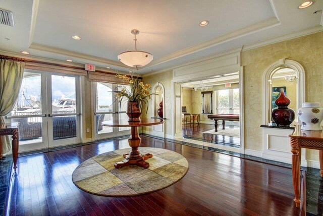 dining room featuring french doors, dark hardwood / wood-style flooring, a raised ceiling, and crown molding