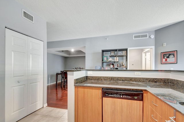 kitchen with paneled dishwasher, visible vents, a textured ceiling, and light tile patterned flooring