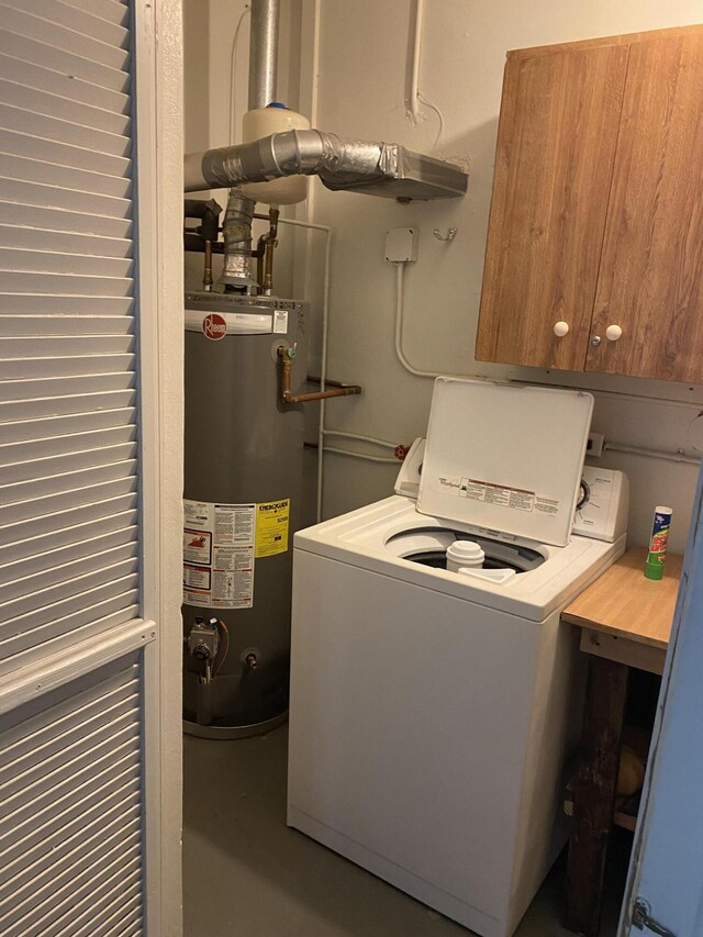 laundry room featuring cabinet space, water heater, and washer / clothes dryer