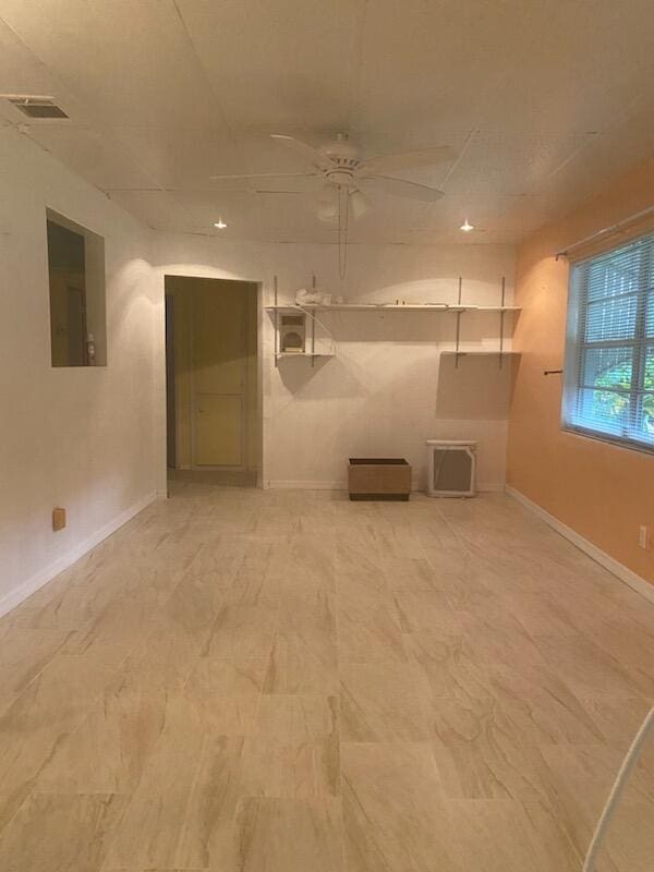 empty room with electric panel, ceiling fan, visible vents, and baseboards