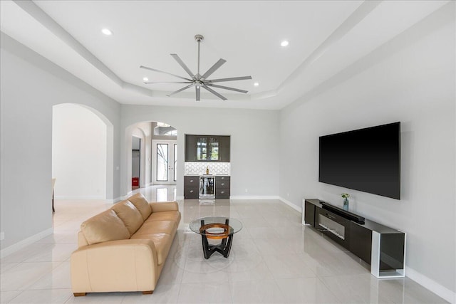 living room featuring beverage cooler, light tile patterned flooring, a raised ceiling, and baseboards