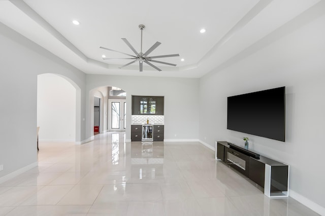 living room featuring beverage cooler, recessed lighting, a raised ceiling, and baseboards