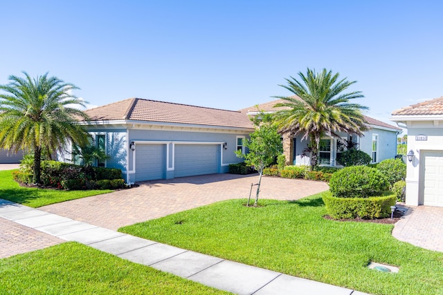 view of front of property with a garage, a tile roof, decorative driveway, stucco siding, and a front yard