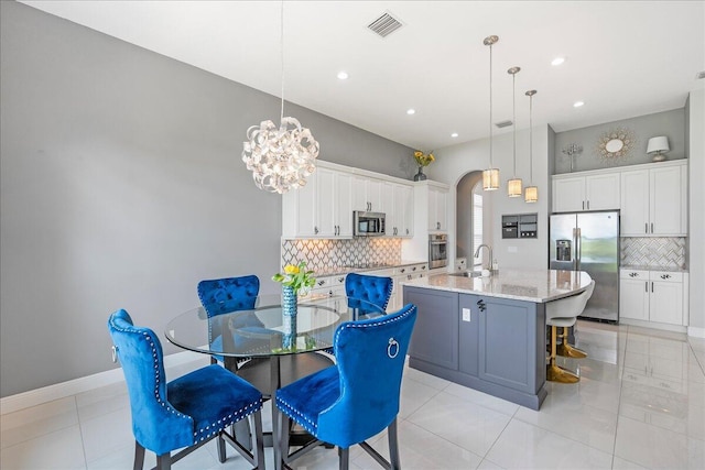 dining space featuring arched walkways, light tile patterned floors, visible vents, an inviting chandelier, and baseboards