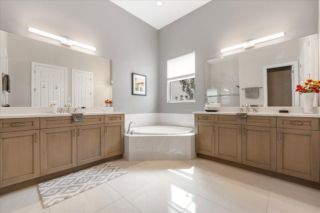 bathroom with two vanities, tile patterned flooring, a garden tub, and a sink