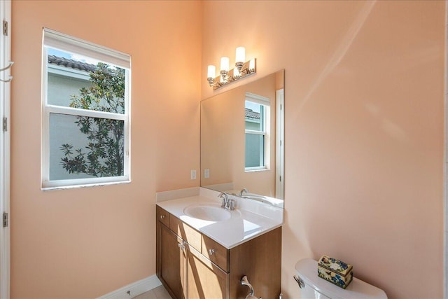 half bathroom featuring baseboards, vanity, and toilet