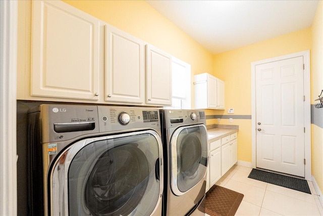 clothes washing area with light tile patterned flooring, washing machine and clothes dryer, and cabinet space