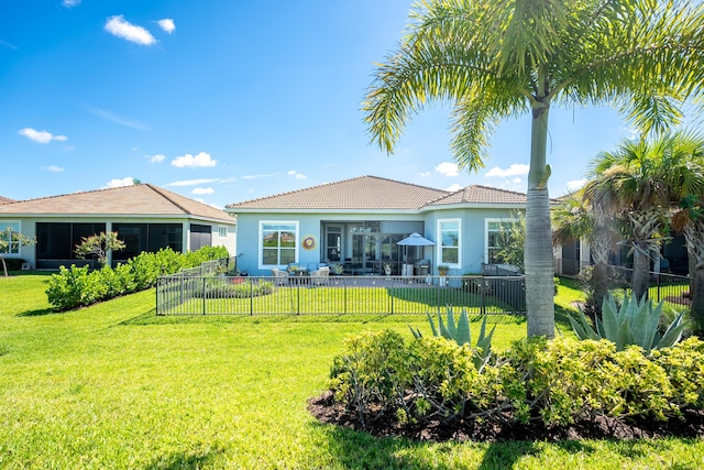 back of property with a yard, a fenced backyard, a sunroom, and stucco siding