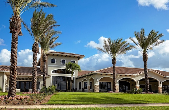 view of front of property featuring a front lawn, a tile roof, and stucco siding