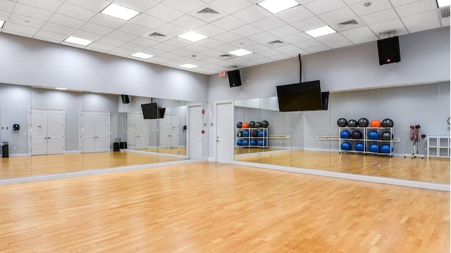 exercise room featuring visible vents, a towering ceiling, and wood finished floors