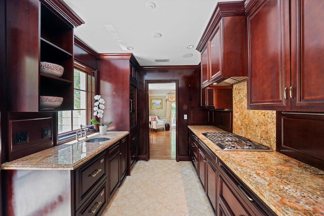 kitchen featuring stainless steel gas stovetop, light stone counters, open shelves, and a sink