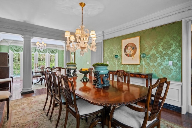 dining room featuring decorative columns, ornamental molding, wainscoting, a chandelier, and wallpapered walls