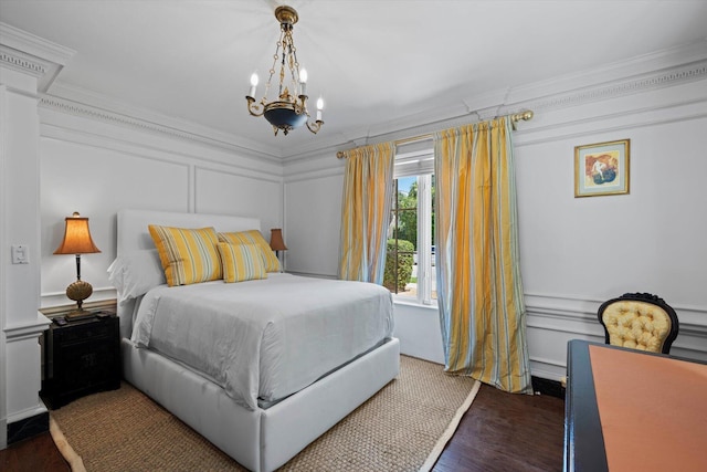 bedroom featuring crown molding, dark wood-type flooring, a chandelier, and a decorative wall