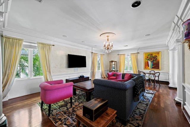 living area with decorative columns, dark wood finished floors, crown molding, a decorative wall, and a notable chandelier