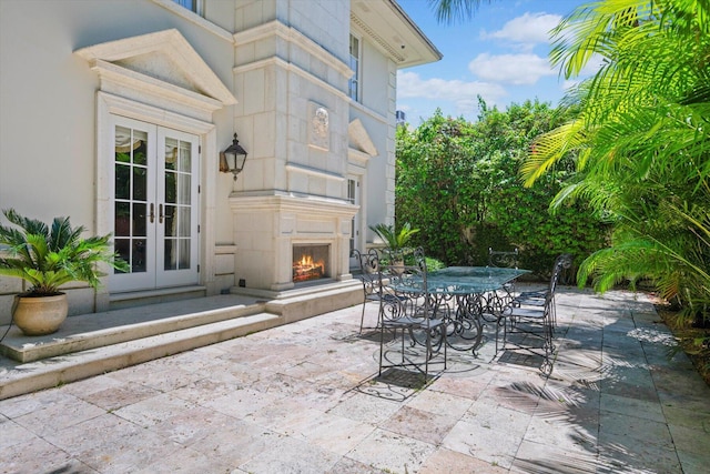 view of patio / terrace featuring a warm lit fireplace and french doors