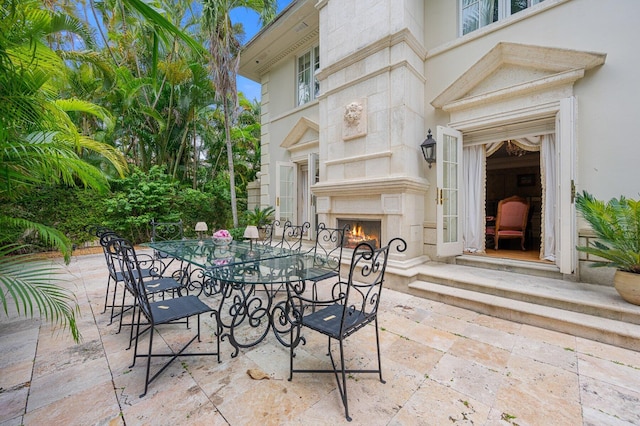 view of patio / terrace featuring a lit fireplace and outdoor dining space