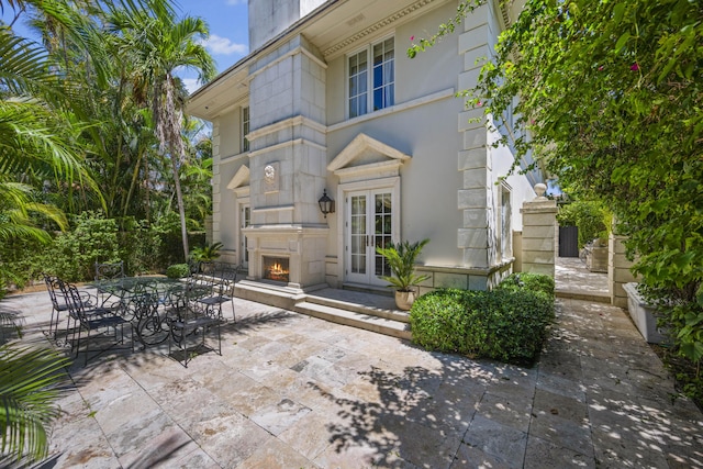 exterior space with a lit fireplace, stone siding, a patio area, and outdoor dining space