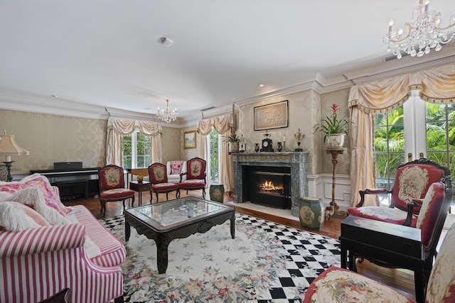 living room featuring a chandelier, a fireplace, wood finished floors, ornamental molding, and wallpapered walls